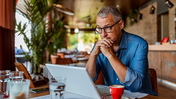 un hombre con gafas sentado delante de un ordenador portátil