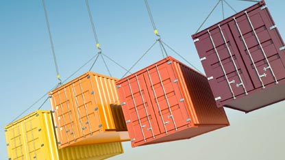 Cuatro contenedores de diferentes colores suspendidos en el aire mediante cadenas